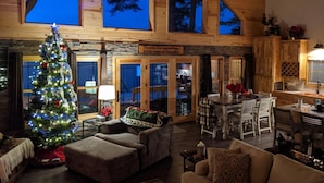 Un intérieur de chalet chaleureux avec un sapin de Noël décoré, un coin repas et une cuisine.