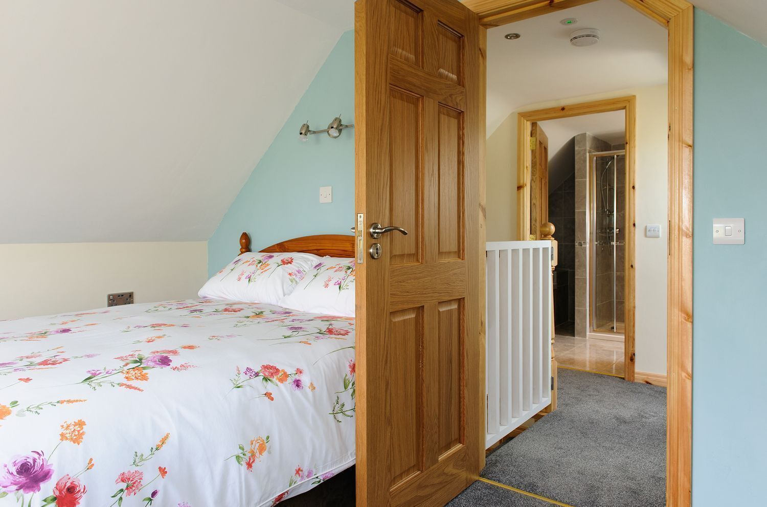 A bedroom with a bed, wooden door, and a view of a bathroom with a shower.