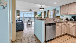 A modern kitchen with a dishwasher, wooden cabinets, and a view to the outside. - Stunning Oceanfront View Atlantica Tower (Myrtle Beach)