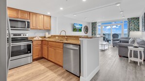 A modern kitchen with wooden cabinets, stainless steel appliances, and a large island. - Stunning Oceanfront View Atlantica Tower (Myrtle Beach)