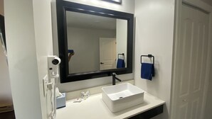Une salle de bain avec un lavabo blanc, un grand miroir et un porte-serviettes.