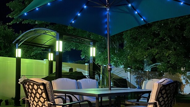 Une terrasse extérieure avec une table et des chaises, un auvent et des guirlandes lumineuses.