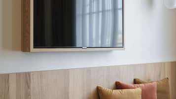 Una sala de estar moderna con un banco de madera, un televisor de pantalla plana montado y una lámpara.