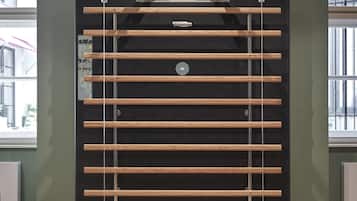 Un gimnasio con una estructura de barra para dominadas, un panel de control y una ventana con vistas a edificios.