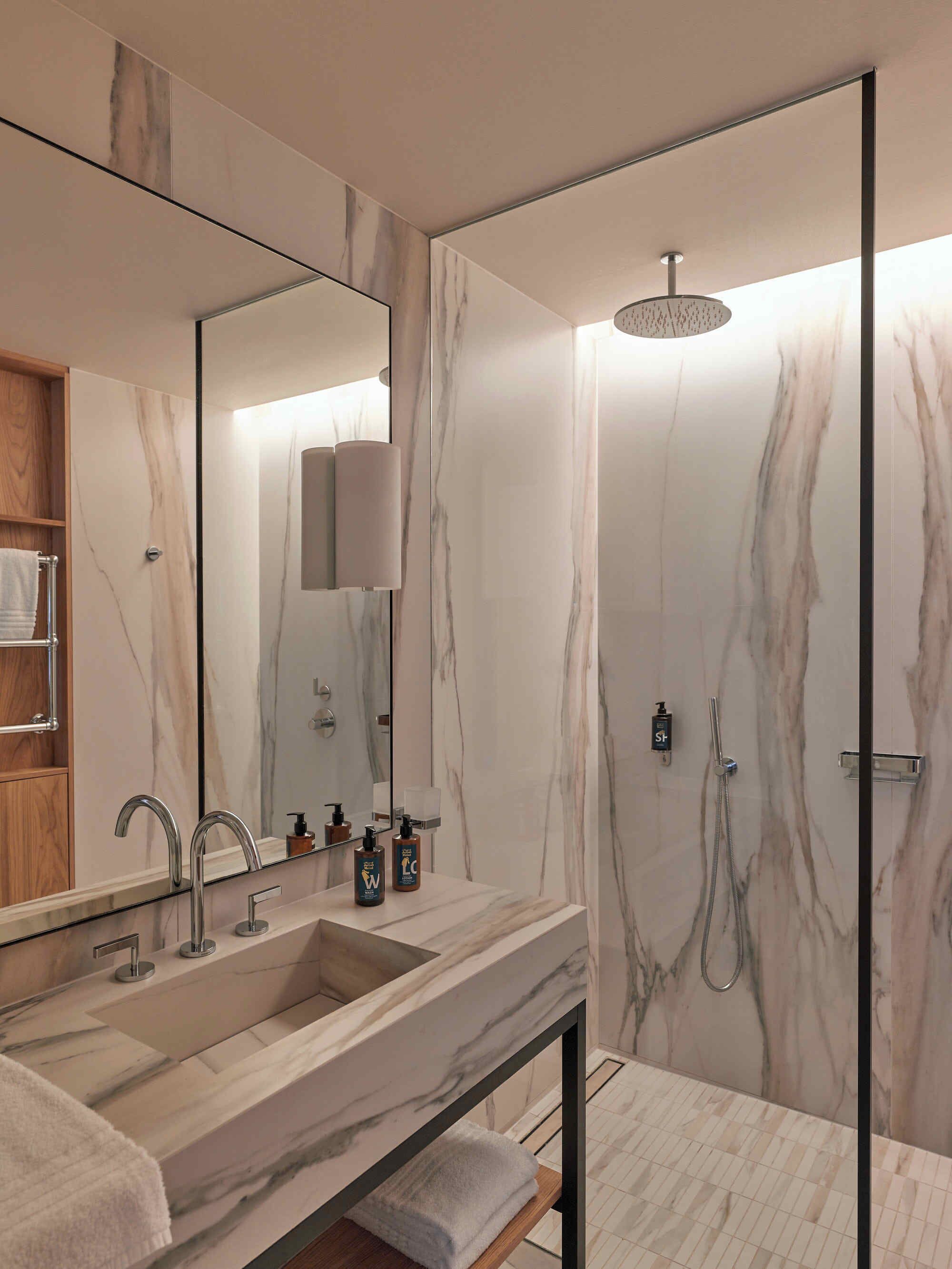 A modern bathroom with a marble sink, a large mirror, and a shower with a glass door.