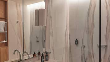 A modern bathroom with a marble sink, a large mirror, and a shower with a glass door.