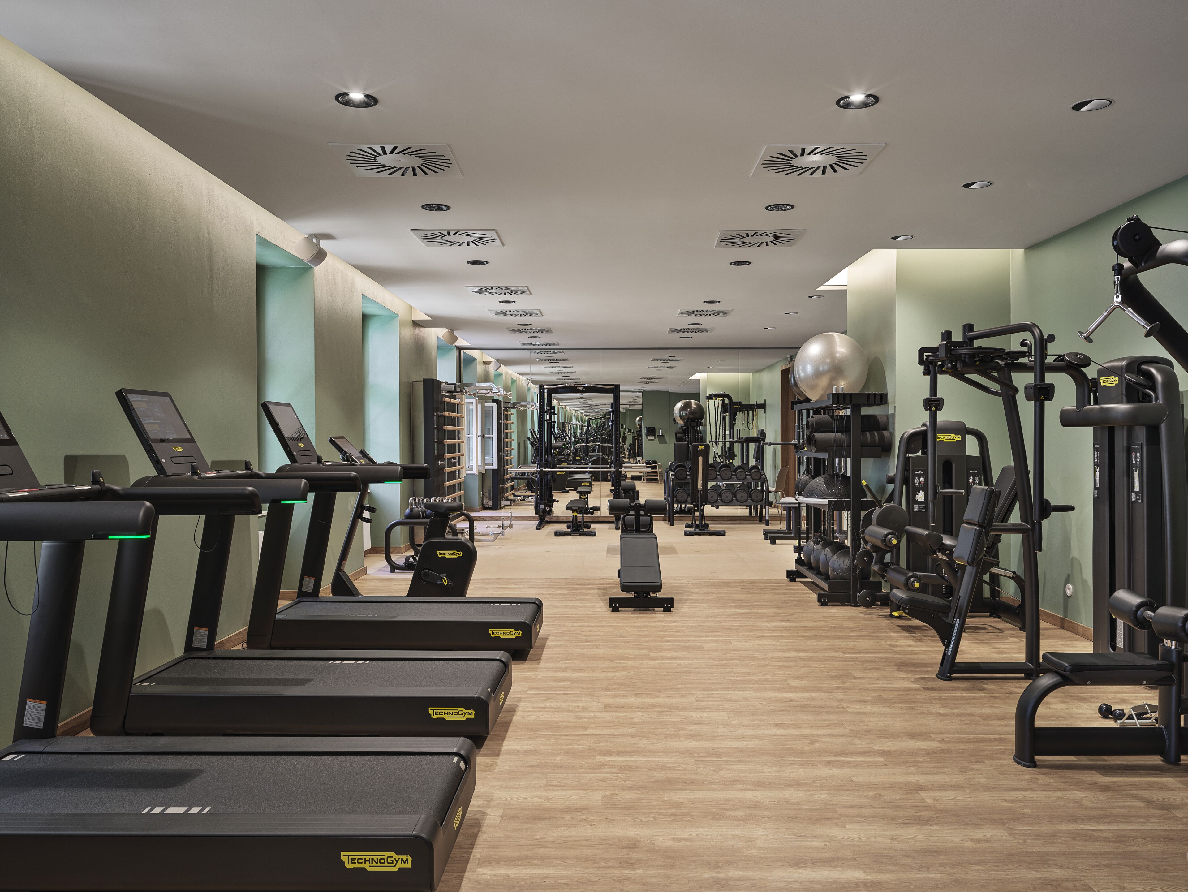 Een fitnessruimte met loopbanden, krachttoestellen en losse gewichten.