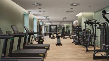 Een fitnessruimte met loopbanden, krachttoestellen en losse gewichten.