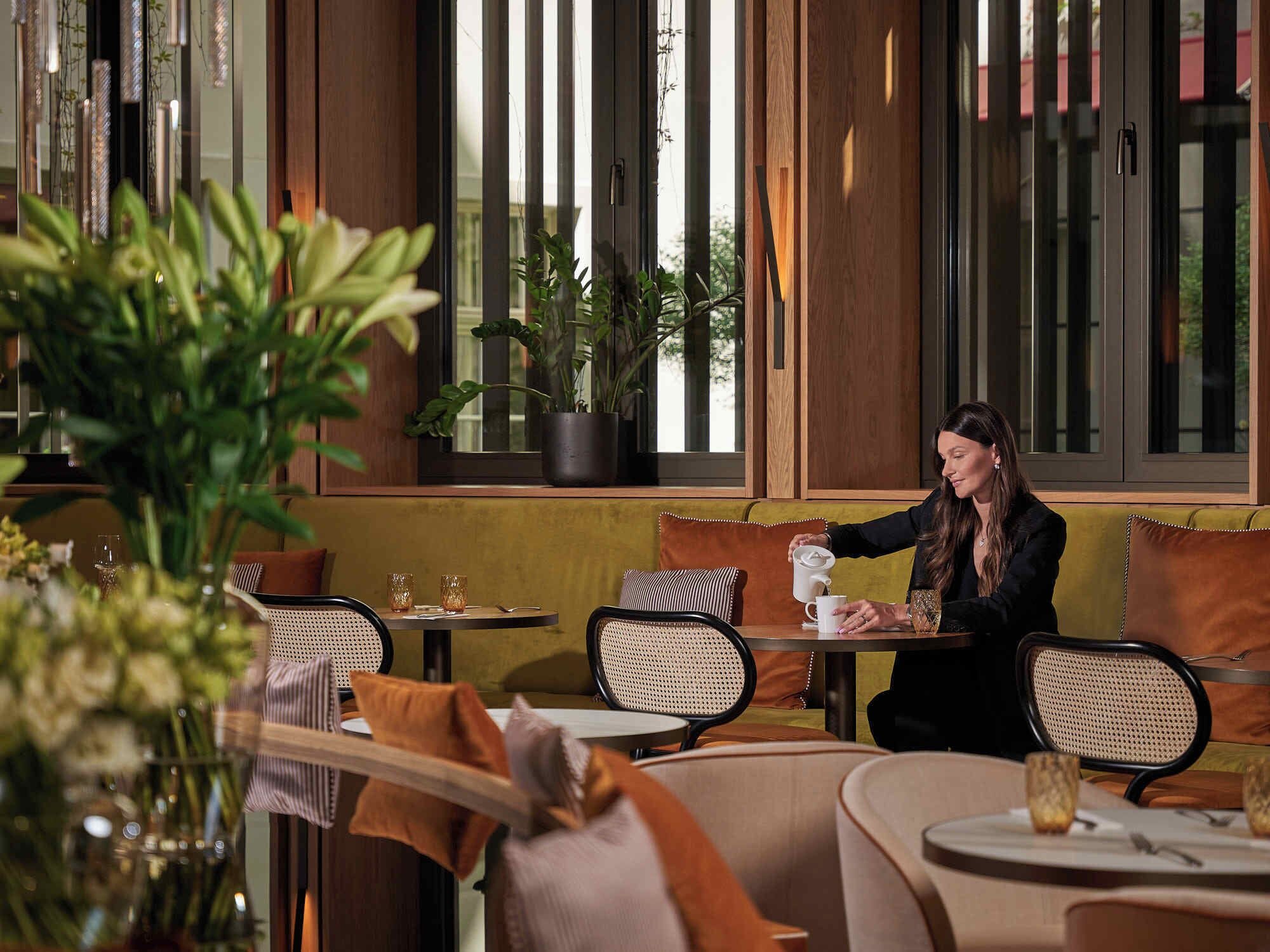 A modern cafe with wooden accents, comfortable seating, and large windows.