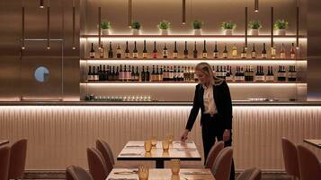 A modern bar area with neatly arranged bottles and a person attending to a table.