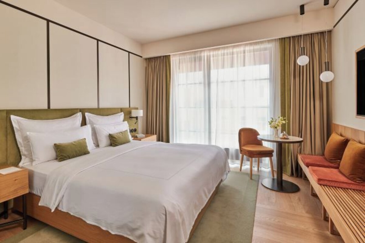 Een hotelkamer met een groot bed, een bureau, een stoel en een bank.