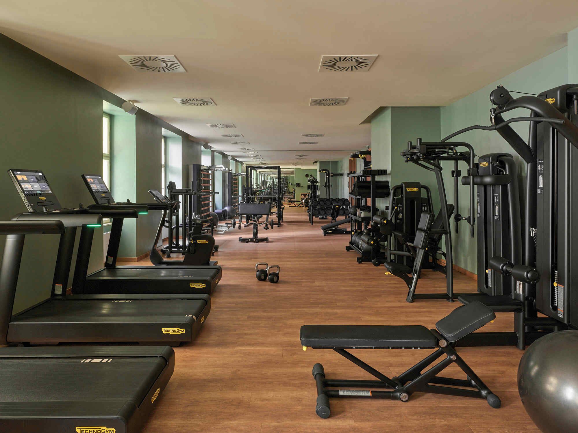 Ein Fitnessstudio mit Laufbändern, Kraftgeräten und Kurzhanteln.