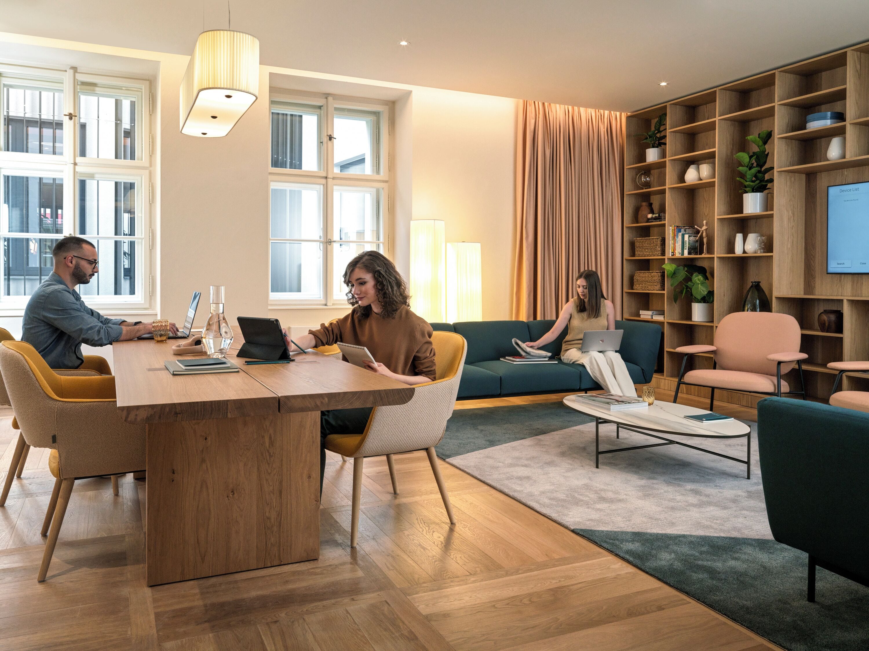A modern living room with a wooden dining table, comfortable seating, a bookshelf, and a television.