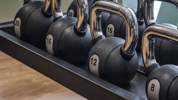 A set of black kettlebells with chrome handles, each marked with a number, arranged on a rack.