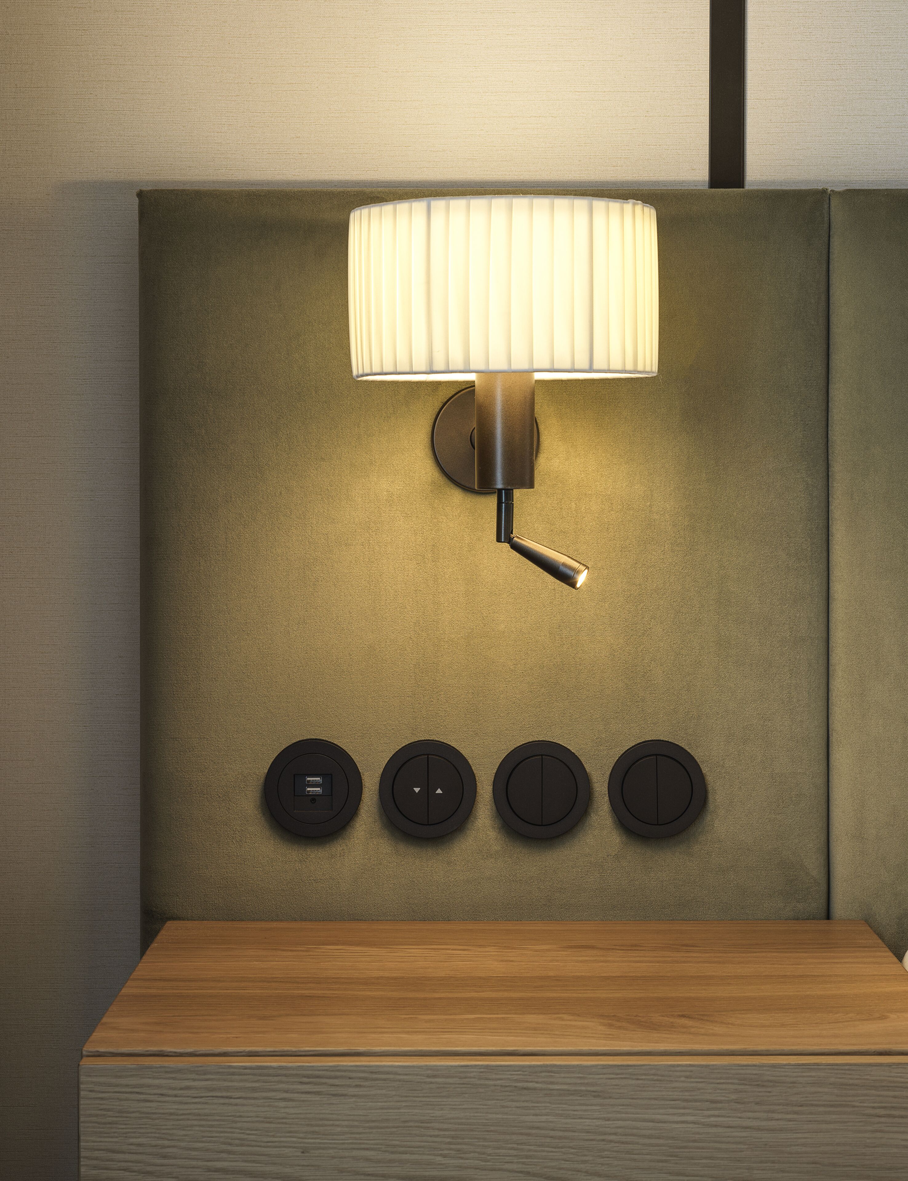 A modern wall-mounted lamp with a pull-down switch and three circular controls below it.