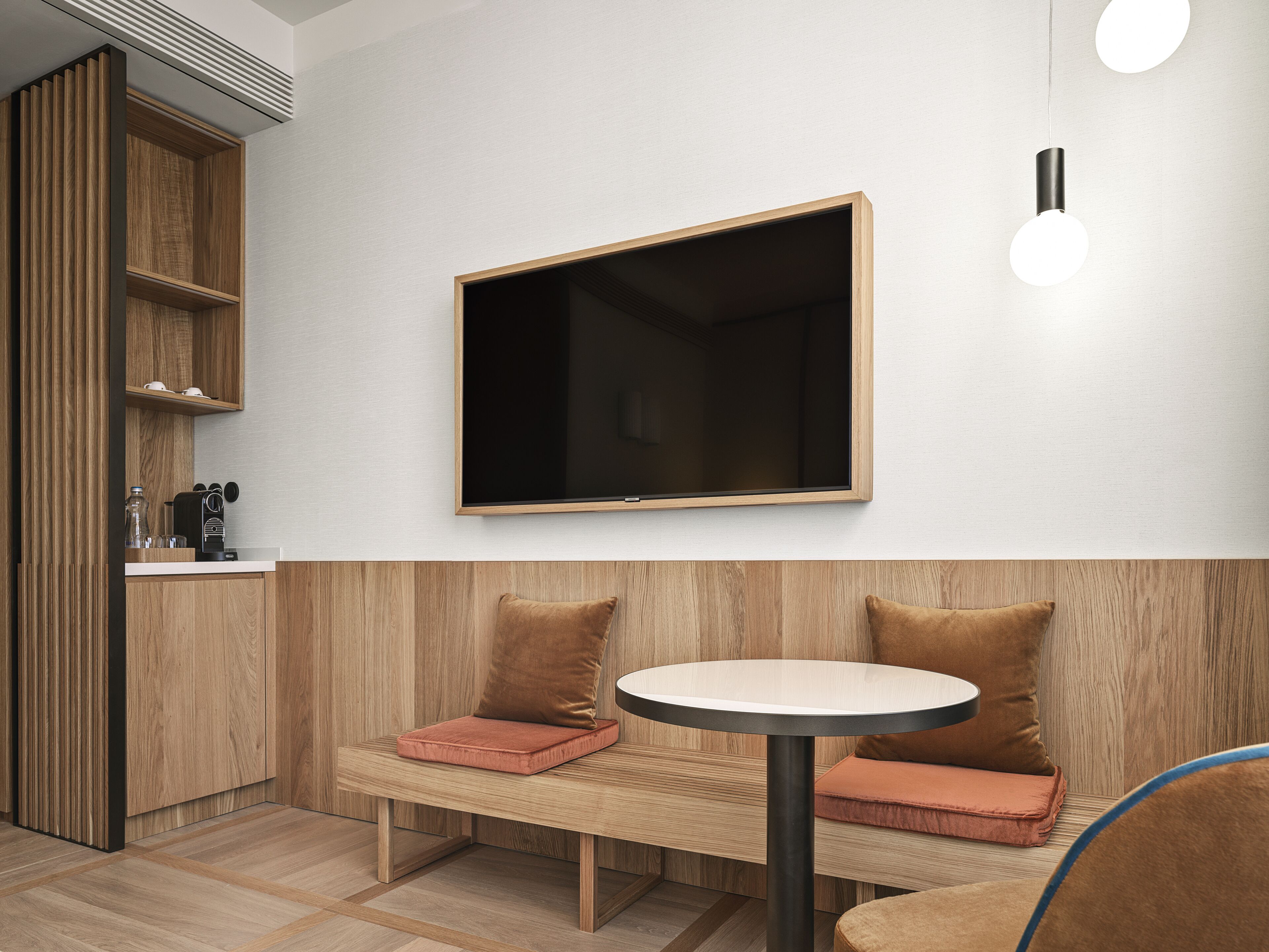 Una cocina moderna con armarios de madera, un banco empotrado con cojines y una mesa redonda.