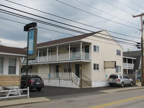 A two-story building with a balcony on the second floor, a sign for 'Saco Bay Condos', and two parked cars. - Large three bedroom condo, steps from beach and amusement area (Old Orchard Beach)