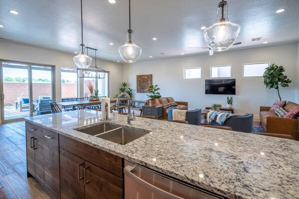 A spacious kitchen with granite countertops, a large island, and modern pendant lighting.