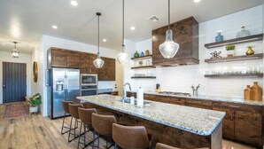 A modern kitchen with a central island, bar stools, wooden cabinets, and pendant lighting. - Arcadia 50 | Shuffleboard * Sleeps 22 * Views of Red Rocks (Santa Clara)