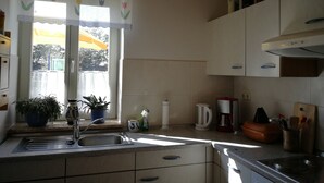 Eine Küche mit Fenster, Spüle, Schränken und verschiedenen Geräten.