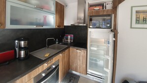 A modern kitchen with wooden cabinets, a stainless steel sink, a coffee maker, and a built-in microwave. - Studio + Mountain corner - 4/6 people - 250m from the ski slopes (Chantemerle)