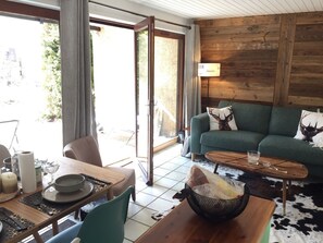 Una sala de estar acogedora con un sofá verde, una mesa de centro de madera y una zona de comedor con una mesa dispuesta para dos.