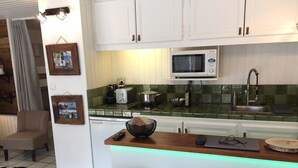 A modern kitchen with white cabinets, a microwave, and a wooden countertop. There is a bowl on the counter and a chair in the dining area. - Nice flat on ground floor - 4-6 people (Chantemerle)