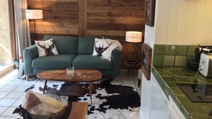 A cozy living room with a green sofa, a wooden coffee table, and a cowhide rug. - Nice flat on ground floor - 4-6 people (Chantemerle)