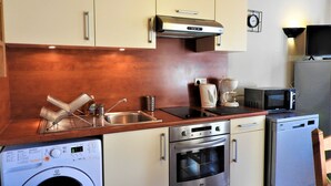 Een kleine keuken met roestvrijstalen apparatuur, een wasmachine en een magnetron.