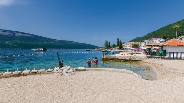 A coastal beach with clear waters, a rocky shoreline, and a few people near the water. - Stunning Home in Herceg Novi With 1 Bedrooms and Wifi (Baosici)