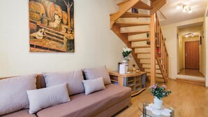 A living room with a wooden staircase, a sofa, a painting, and a vase with flowers. - Awesome Home in Rovinj With Wifi and 0 Bedrooms (Rovinj)