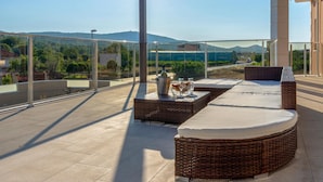 A covered outdoor seating area with wicker furniture and a glass balustrade overlooking a scenic landscape. - Nice Home in Dubrava kod Sibenika With Outdoor Swimming Pool, Wifi and 5 Bedrooms (Sibenik)
