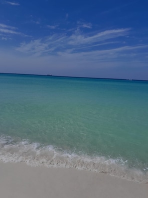 Una playa con agua turquesa transparente y una orilla arenosa.