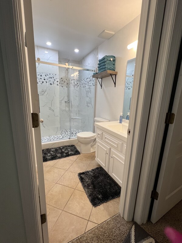 Un baño moderno con cabina de ducha de vidrio, inodoro, lavabo y espejo.