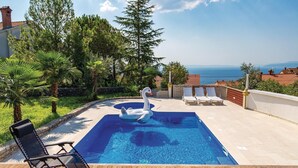 Ein Swimmingpool mit einer Schwane als Schwimmtiermotiv, umgeben von Palmen und Blick aufs Meer.