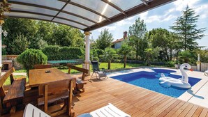Eine Holzterrasse mit Schwimmbad, Liegestühlen und einem Schwaneinrad.