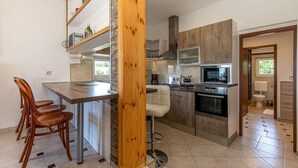 A compact kitchen with a central island, wooden chairs, and a built-in stove. - Stunning Home in Smrika With Wifi and 3 Bedrooms (Kraljevica)