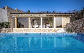 A modern house with a pool, stone walls, and a patio area with outdoor furniture. - Amazing Home in Dramalj With Wifi, 2 Bedrooms and Outdoor Swimming Pool (Crikvenica)