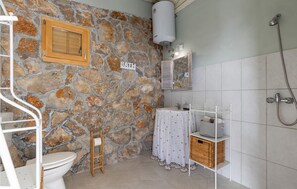 A bathroom with a stone wall, a toilet, a sink with a white cloth, a shower, and a sign that reads "BATH". - Amazing Home in Dramalj With Wifi, 2 Bedrooms and Outdoor Swimming Pool (Crikvenica)