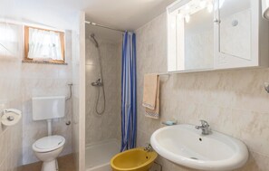 Un baño con inodoro, ducha con cortina, lavamanos y espejo.