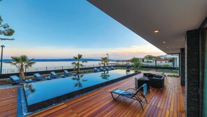 A wooden deck with a pool, lounge chairs, and a view of the sea. - Beautiful Home in Kastel Stari with Hot Tub, Sauna & Outdoor Swimming Pool (Kastela)