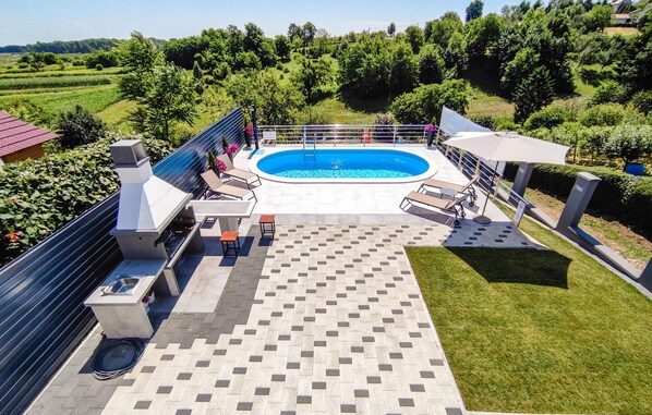 A rooftop pool area with a tiled floor, lounge chairs, and a barbecue grill.
