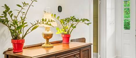 Un aparador de madera con dos plantas en macetas y una lámpara de bronce.