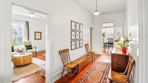 A spacious room with hardwood flooring, a dining area with wooden chairs, a bench, and a colorful rug. - Mountain View Cottage | Wine, Hiking & Dog Friendly (Afton)
