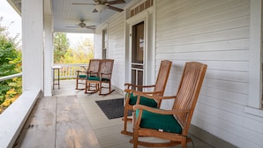 A porch with wooden chairs and a table, a ceiling fan, and a view of trees. - Mountain View Cottage | Wine, Hiking & Dog Friendly (Afton)