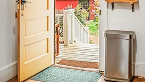 A wooden door leading to a balcony with a view of a house and mountains. - Mountain View Cottage | Wine, Hiking & Dog Friendly (Afton)
