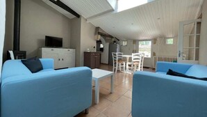 A modern living room with two blue sofas, a small white table, and a kitchen area with a dining table and chairs. - Isis, small house, South Vendée, Puy du fou, Marais Poitevin (CEZAIS)