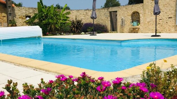 A swimming pool with a stone wall and a few umbrellas. - Isis, small house, South Vendée, Puy du fou, Marais Poitevin (CEZAIS)