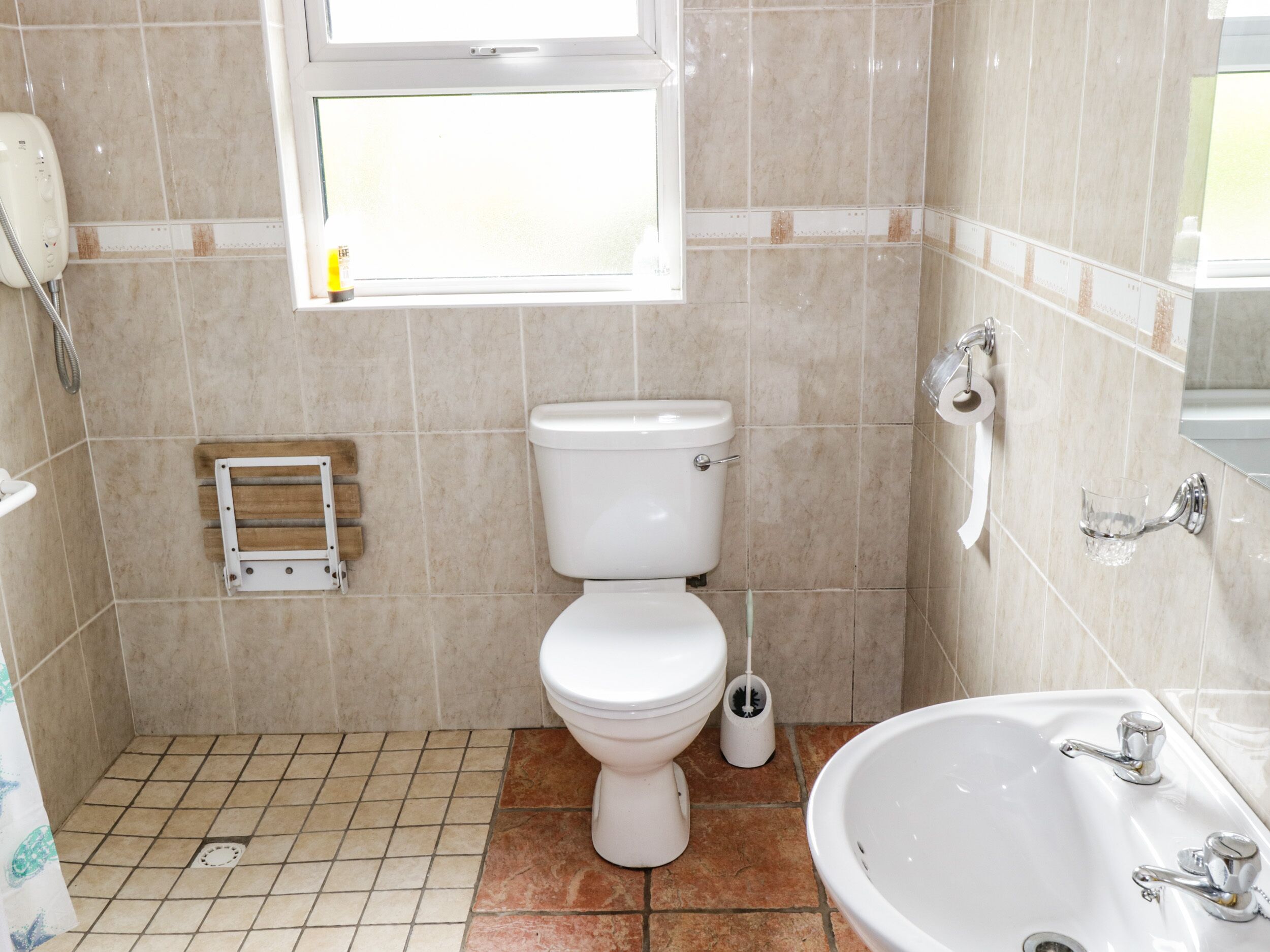 Een badkamer met toilet, een hygiëneschuimer, douche en wastafel.