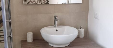 A bathroom with a white sink, a mirror, and a patterned wall.